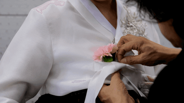 한복에 꽃을 다는 모습