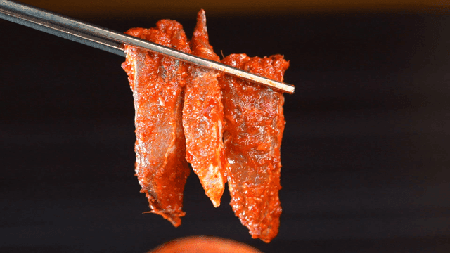 Chopsticks holding spicy marinated fish