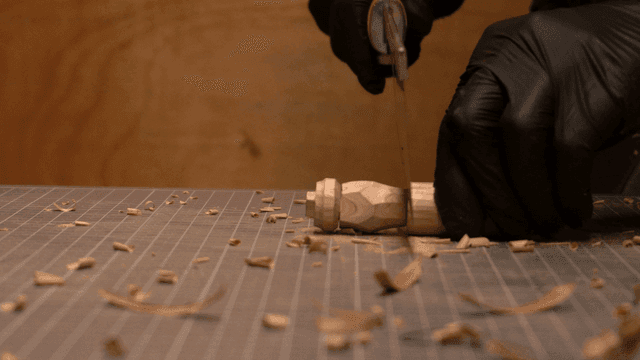 톱으로 나무 조각의 윗부분을 잘라내는 장인