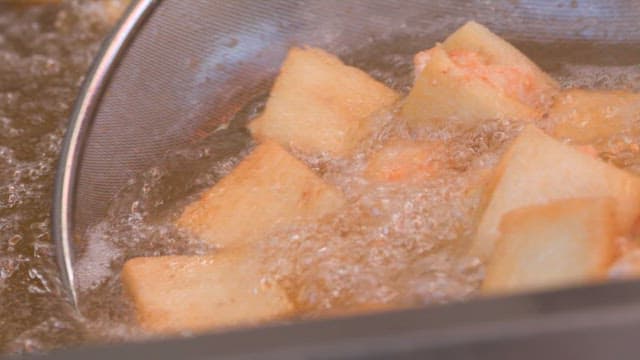 Freshly made golden-brown fried fish in boiling oil