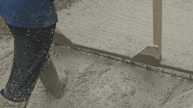Worker smoothing wet concrete surface