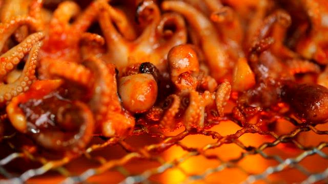 Sizzling small octopuses on a grill