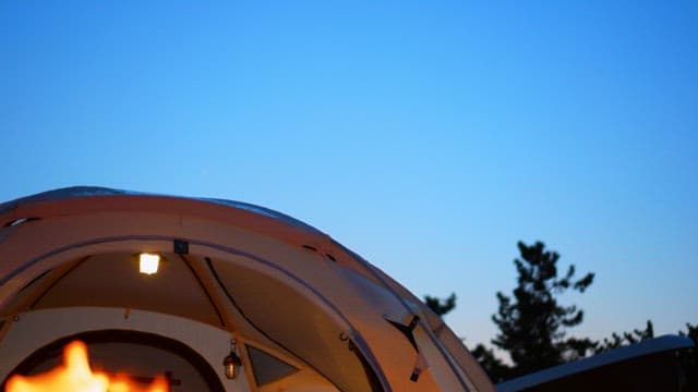 Brightly lit tent under a evening sky