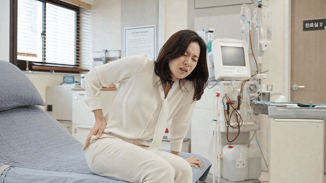 Female patient clutching her stomach and experiencing pain in doctor's office