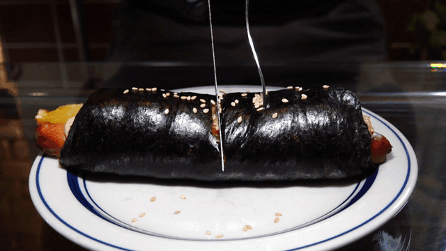 접시에 놓인 김밥 모양 빵을 자르는 장면