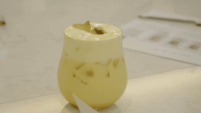 Yellow drink with cream on table