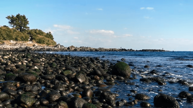 파도와 맑은 하늘이 있는 바위 해변