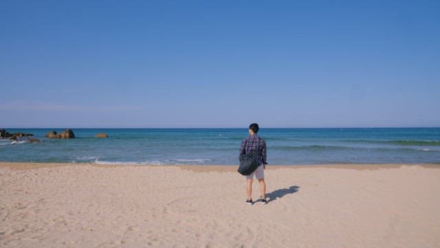 Man Contemplating the Sea from a Sandy Beach