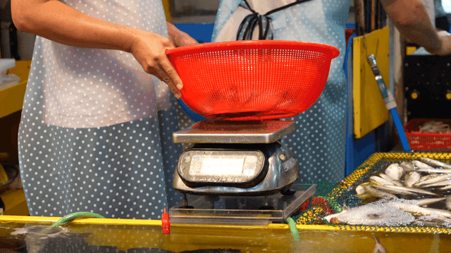 Merchant weighing fish at seafood market