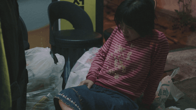 구토한 티셔츠를 입고 쓰레기 위에 누워 휴지를 받는 여성