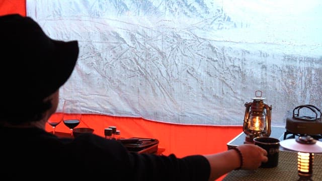 Enjoying a warm drink inside a cozy tent on a rainy day