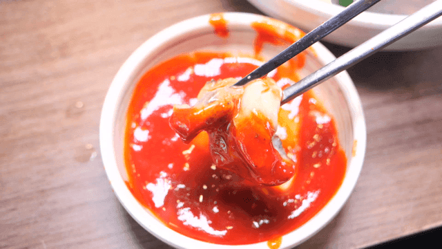 Oyster being dipped in red chili sauce