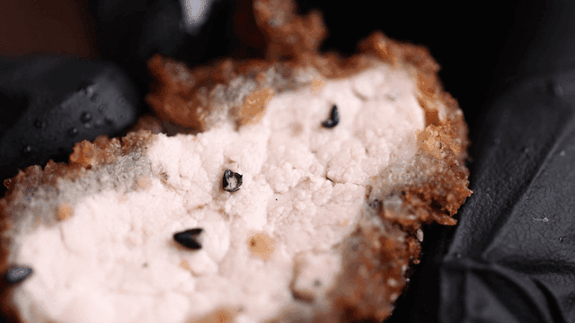Crispy pork cutlet held in gloved hand