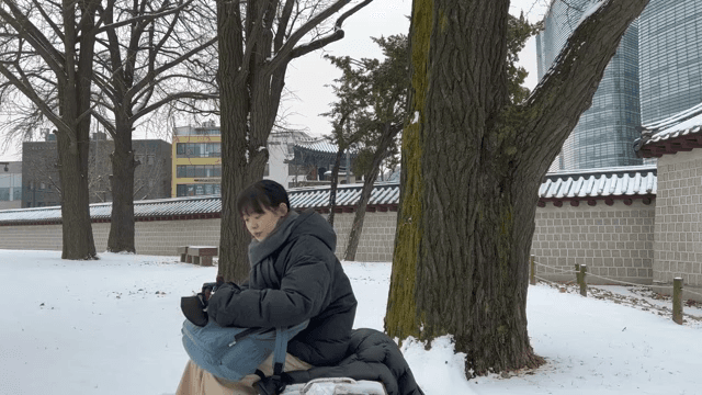 겨울 눈 덮인 벤치에 앉아 있는 여성