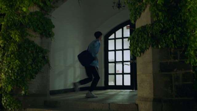 밤에 담쟁이 덩굴로 둘러싸인 건물 안으로 뛰어들어가는 남성