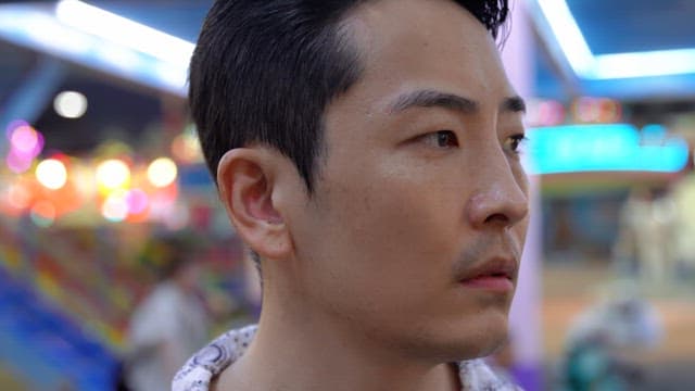 Man in a colorful amusement park at night