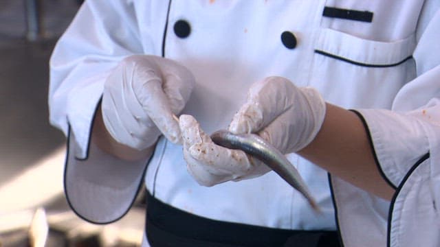 Chef preparing sand eels with skewers in a kitchen