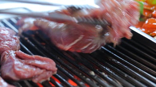 Grilled pork parts sizzling on a restaurant's barbecue grill