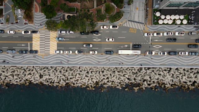 방파제가 있는 해변가 도로에서 움직이는 차량들