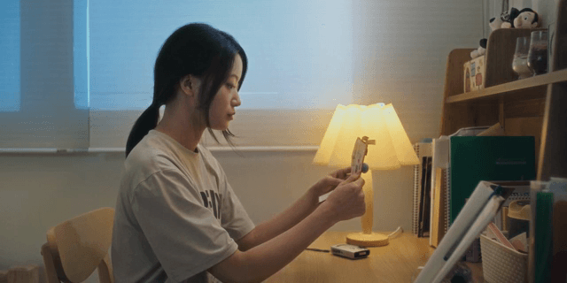 책상에 앉아 편지를 열어보는 여성