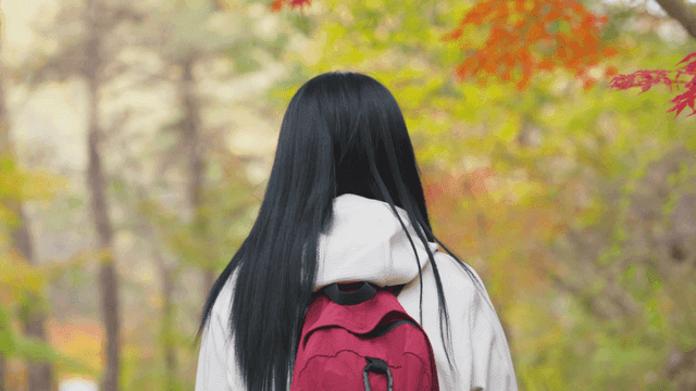 Woman walking through autumn foliage forest