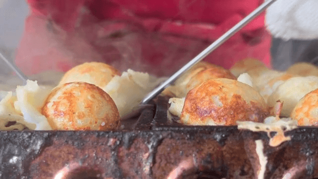 Cooking takoyaki on a hot griddle
