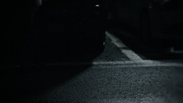 Feet of a Suspicious Person Walking through a Dark Parking Lot at Night