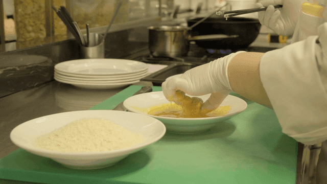 Chef dipping fried food in egg water in kitchen