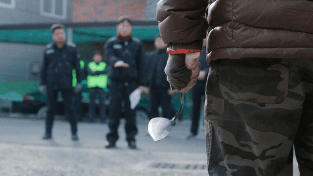 Person holding hoe confronting others