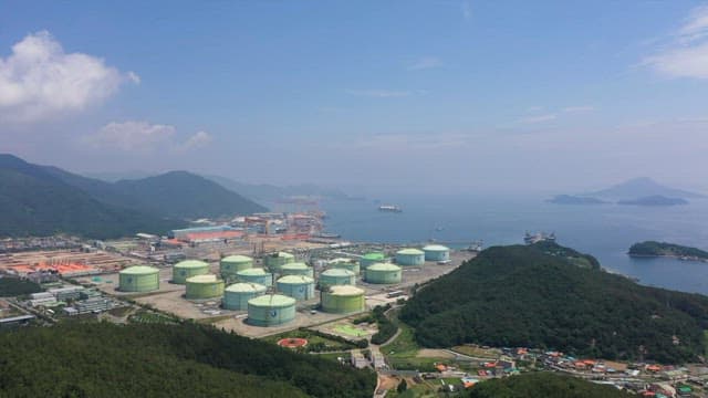 녹색 언덕과 바다가 있는 해안 근처의 공장