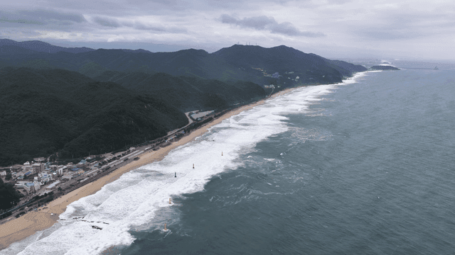 Waves crashing beneath vast mountain range