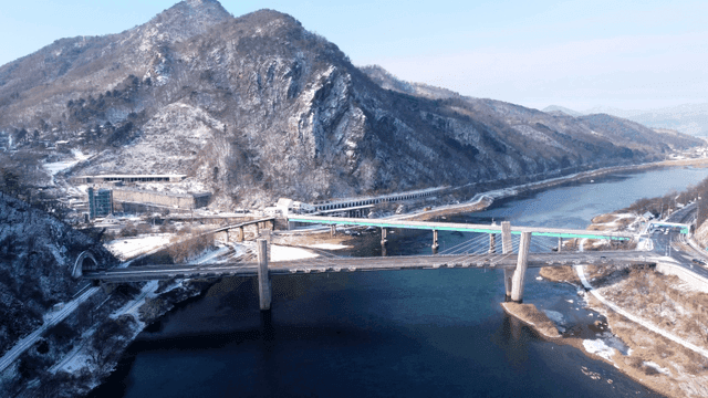 Snow-covered mountains and a bridge over a river