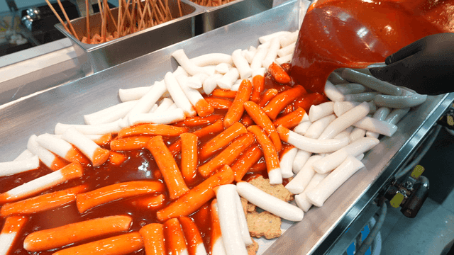 Pouring spicy sauce over rice cakes