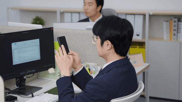 사무실 책상에서 스마트폰을 사용하는 남성