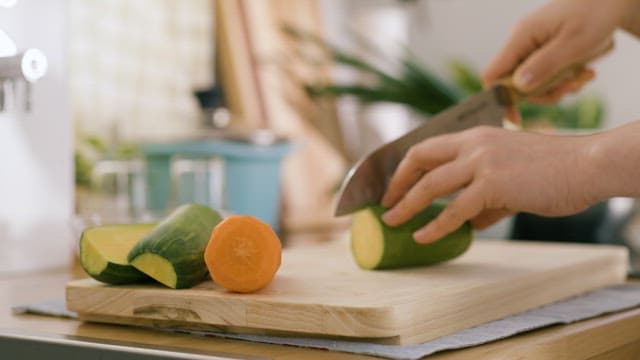 Hands Cuttinf Fresh Vegetables on Cutting Board in Kitchen