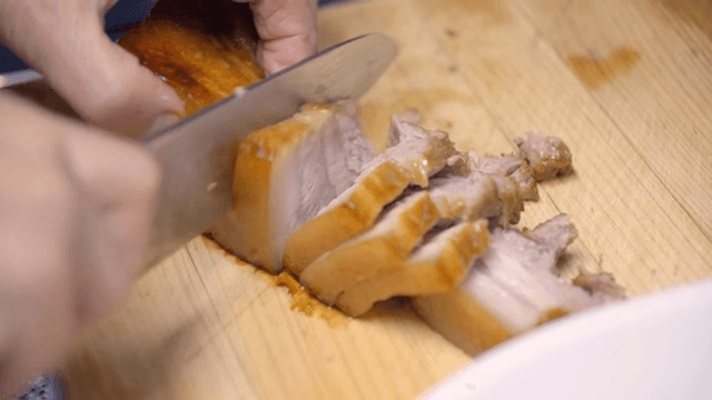 Slicing boiled pork on a wooden board