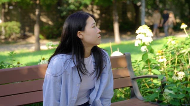 Woman sitting on a bench smiling and saying hello