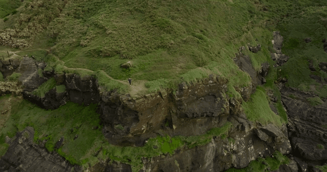 Person running along a green cliff
