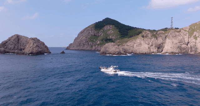 바위 섬 근처를 항해하는 배