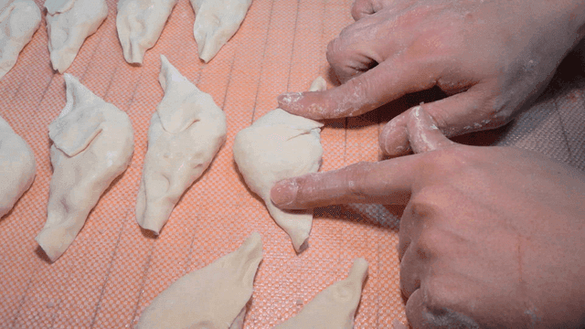 쟁반 위에 만두를 눌러 모양을 잡는 손