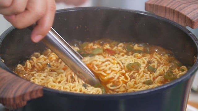 Boiling hot ramen noodles being served in a metal bowl