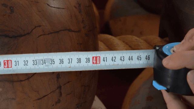 Measuring a wooden object with a tape