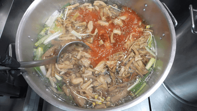 With a ladle loosening the spicy sauce