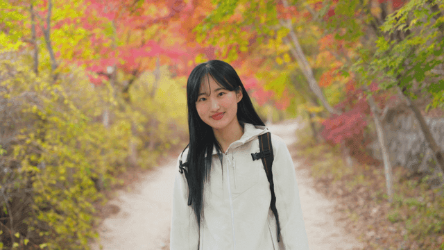 Young woman walking along colorful autumn path
