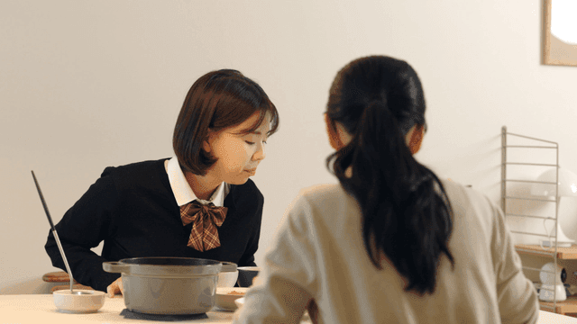 High school daughter eating breakfast with her mother before going to school.