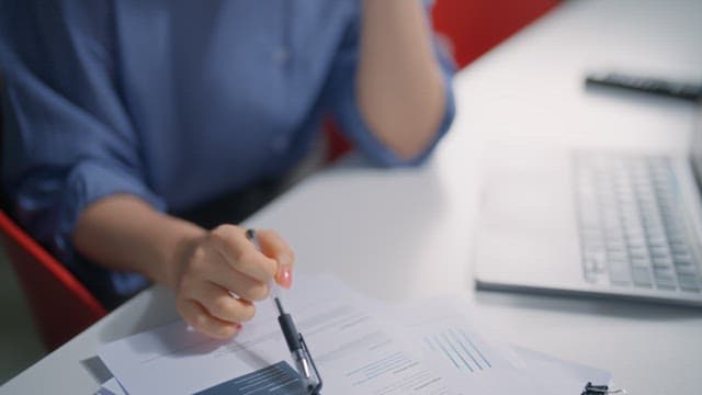 서류가 올려진 책상에서 고민하는 손