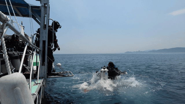Divers jumping into the ocean from a boat
