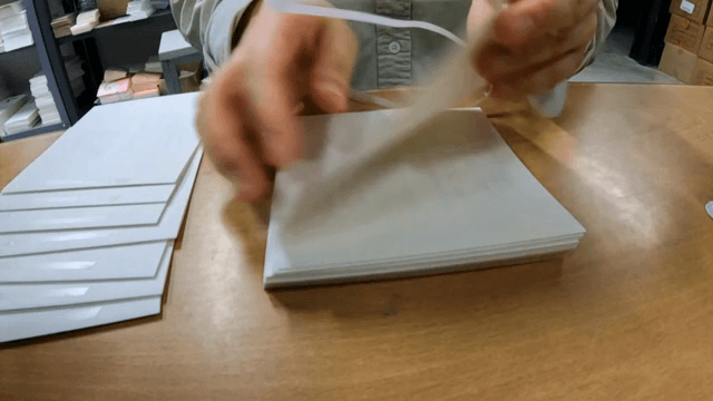 종이 더미에 테이프를 붙이는 손