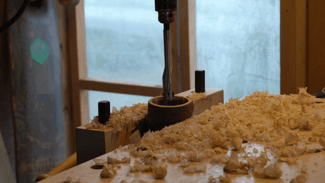Woodworking with an electric drill widening holes in the workshop