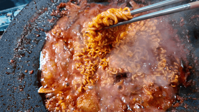 Ramen noodles boiling in spicy chicken stew broth